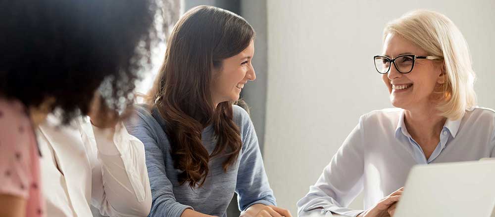 A trio of professionals are sitting around a table having a discussion.