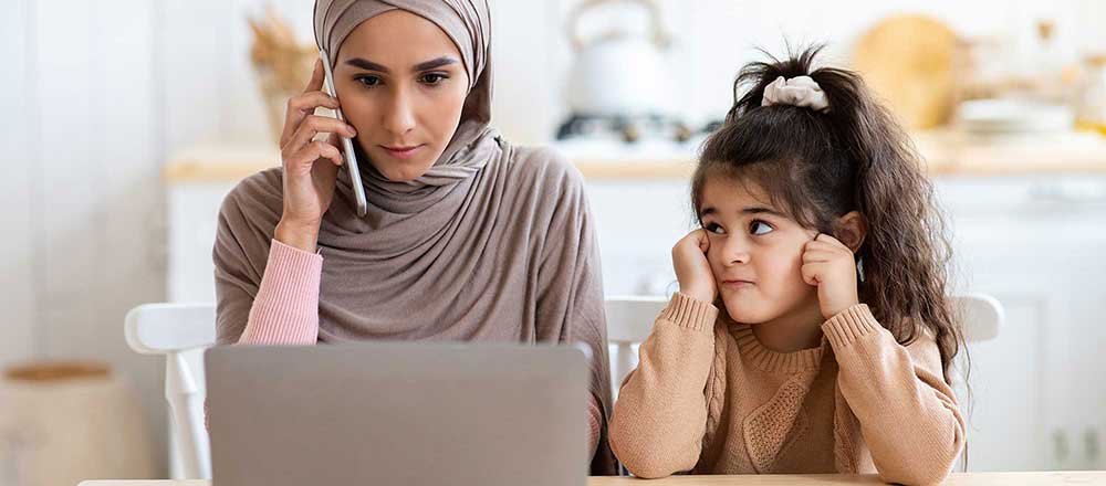 A mother is on the telephone. Her daughter is looking nervous about what her mum is saying