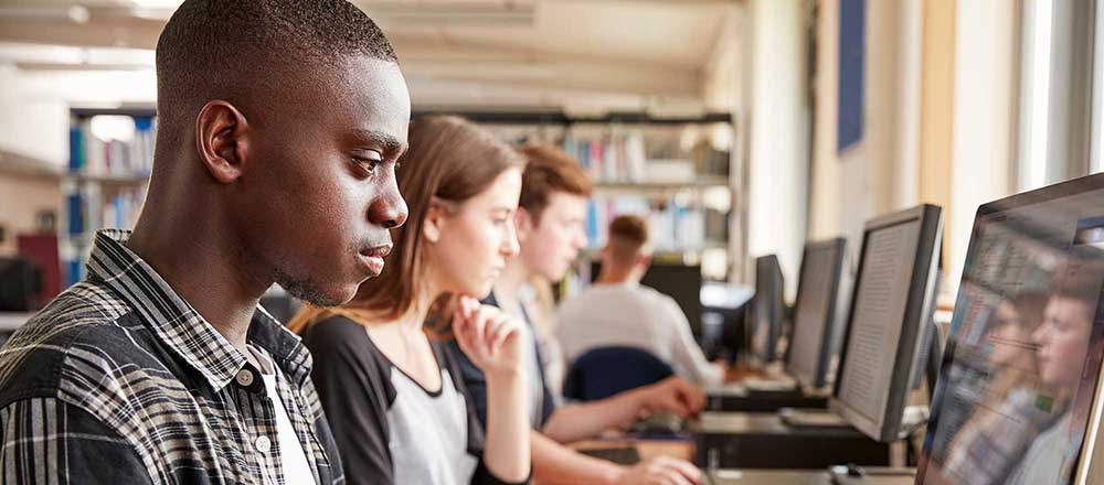 A row of students are sat in front of their computers at their college