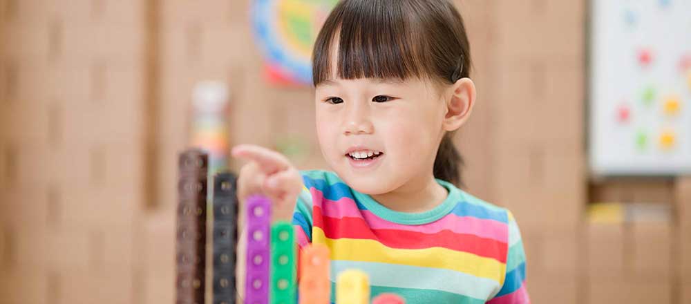 A young girl smiles whilst playing with an educational toy