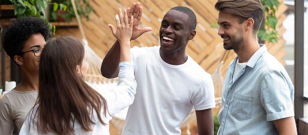 A group of students laugh whilst two of them high-five each other